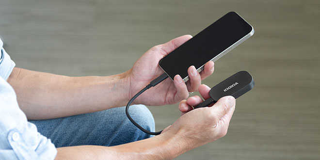 A man holding the EXCERIA PLUS G2 Portable SSD hooked up to a smartphone
